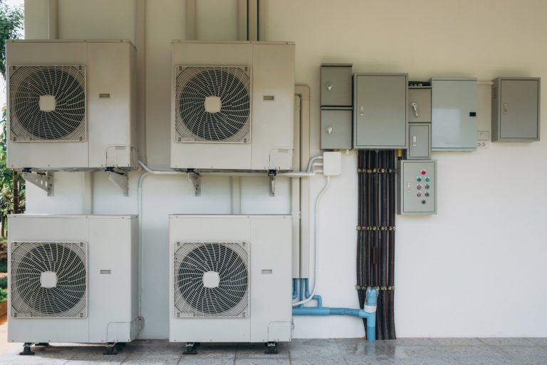 A row of air conditioners are mounted on a wall